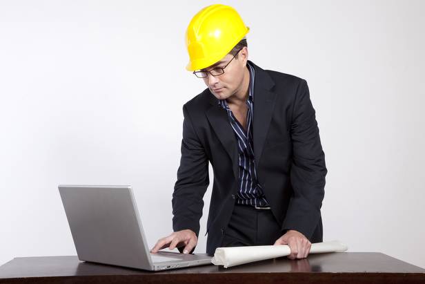 Haciendo arquitectura con las ideas y usando instrumentos Imagen de un profesional arquitecto con planos en mano frente a su computadora portátil