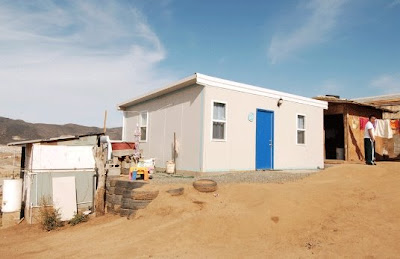 Vista en perspectiva de una casa nueva en el punto más elevado del terreno Arial Home casa de bajo costo levantada por voluntarios